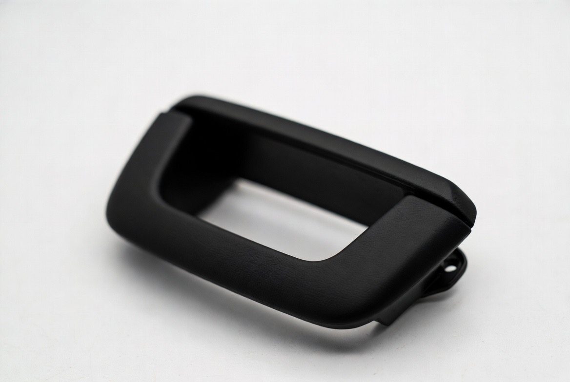 Integral skin urethane automotive interior door handle bezel with leather-grain surface texture and molded-in mount